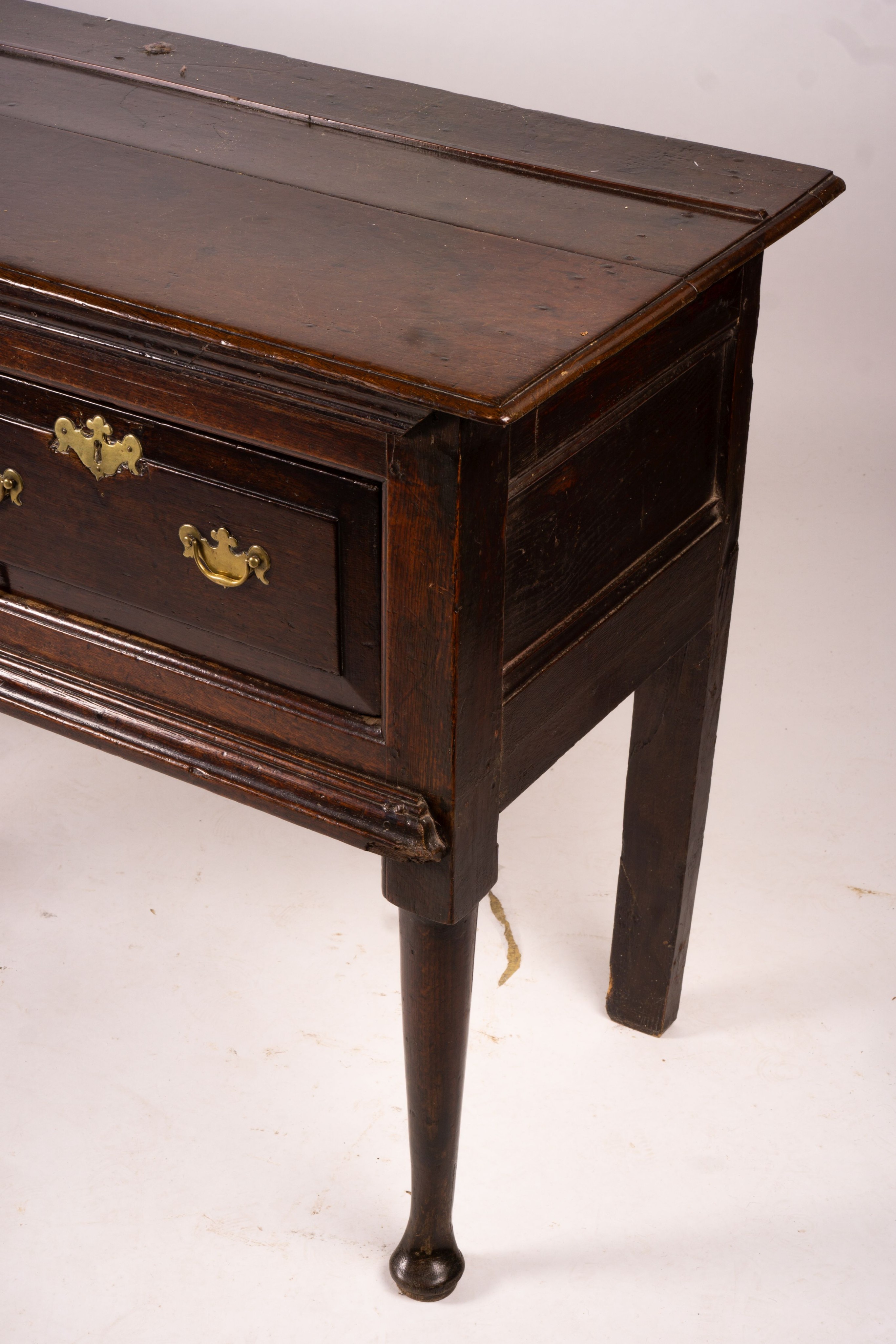 An 18th century oak low dresser on pole turned legs and pad feet, length 198cm, depth 53cm, height 88cm